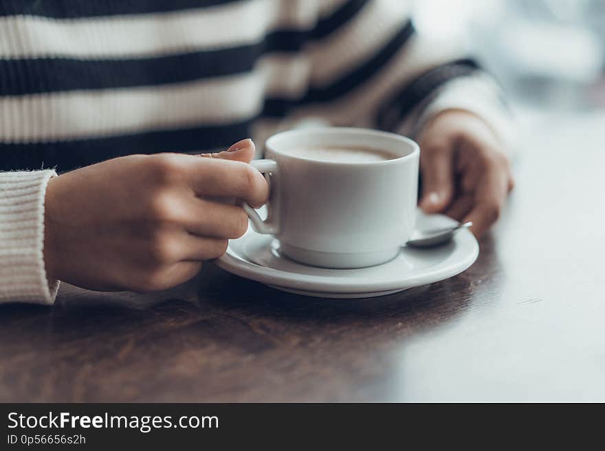 Young girl holding cup of coffe in cafe. waiting something. Horizontal