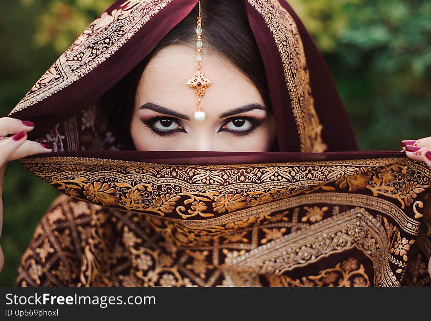 Portrait of beautiful indian girl . Young hindu woman model with tatoo mehndi and kundan jewelry.