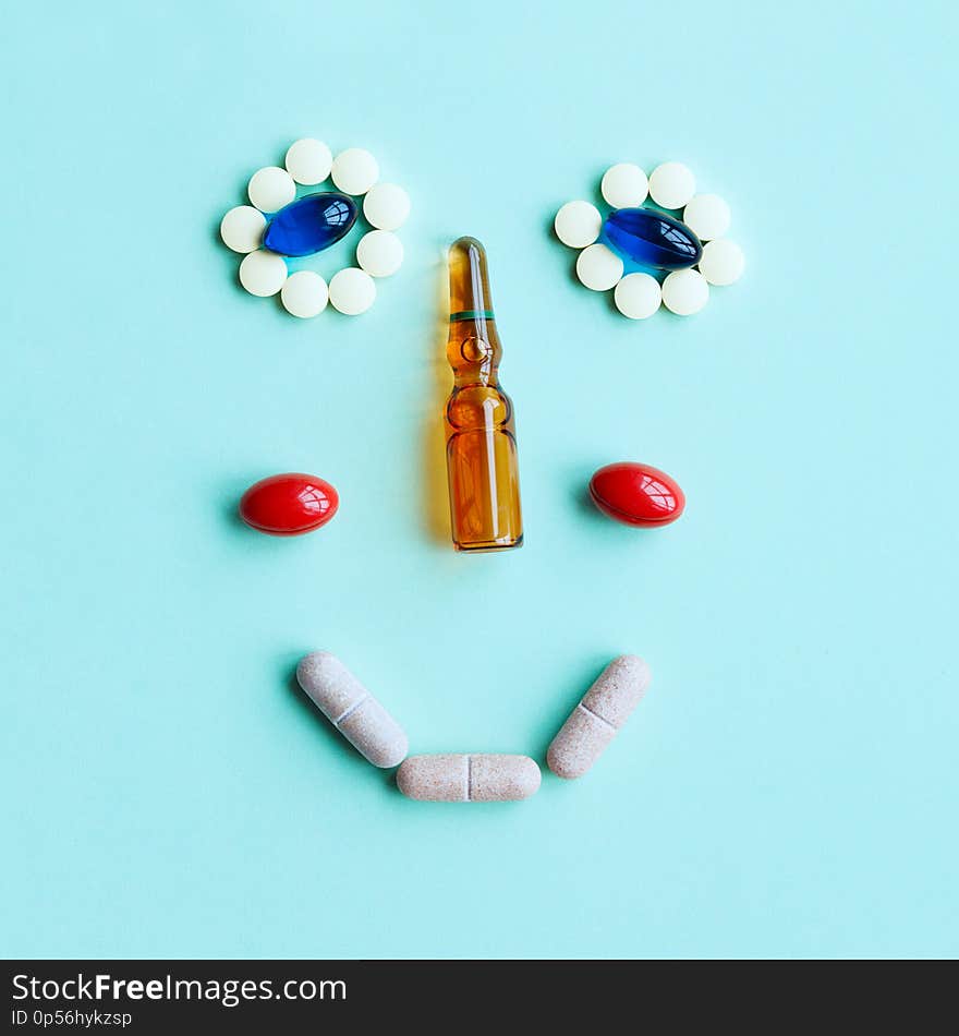 Cute smiling face made of tablets, capsules and an ampule as a nose, don`t be afraid of going to a doctor concept