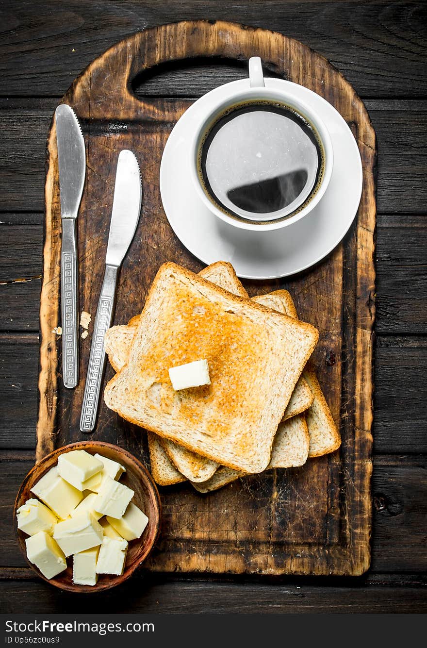 Toasted bread with butter and coffee. On a wooden background