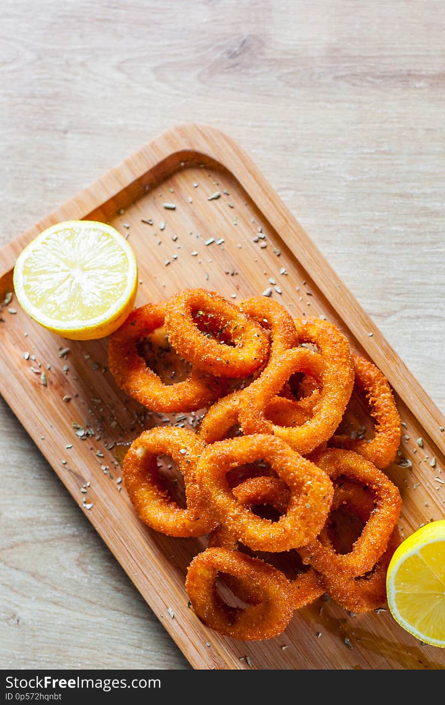 Fried squid rings breaded with lemon on wooden table background