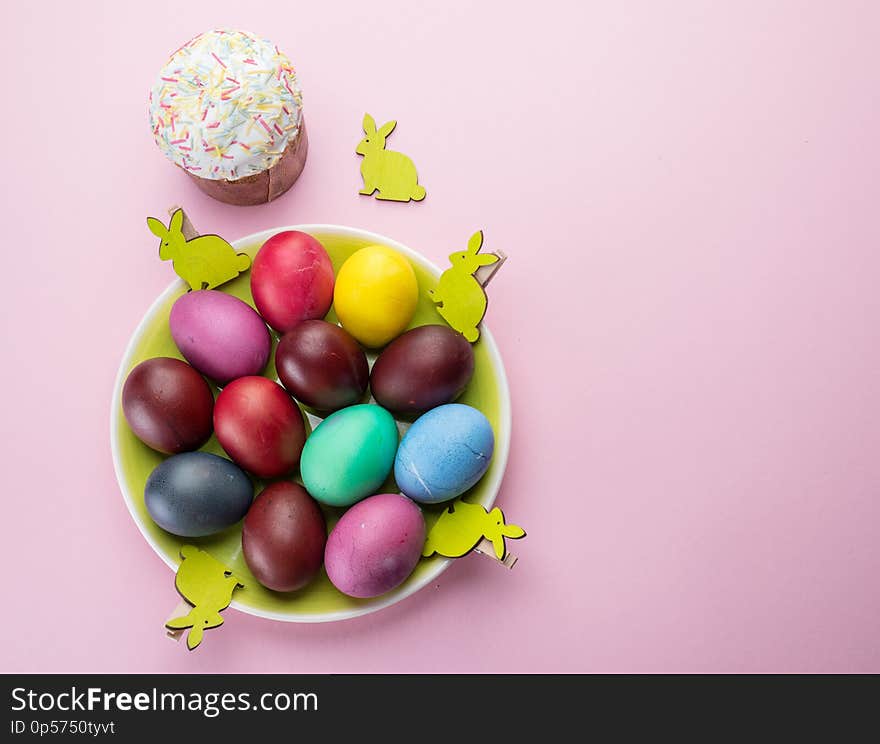 Colorful Easter eggs and Easter bread attributes of Easter celebration. Pink background.