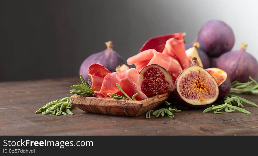 Prosciutto with figs and rosemary on a old wooden table