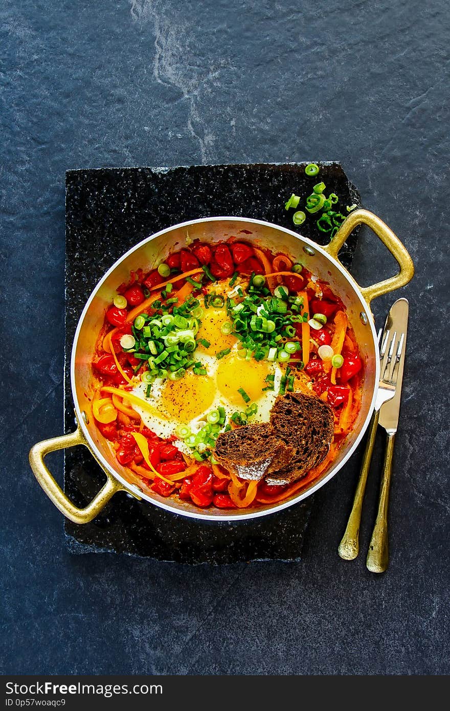 Shakshuka Fried eggs and tomatoes in frying pan on dark background copy space flat lay - Image