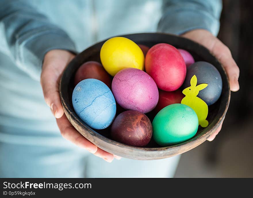 Colorful Easter eggs in bowl in woman`s hands