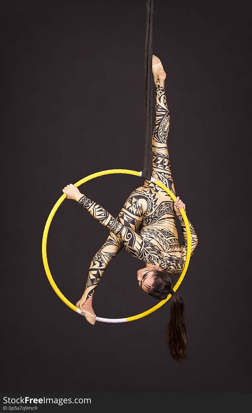 A Young Girl In A Suit With A Print Performs Acrobatic Elements In The Air Ring