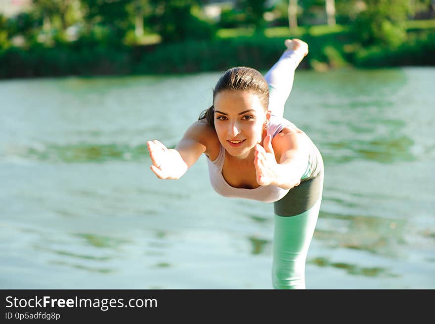 Beautiful young woman meditating in yoga pose at a mountain stream