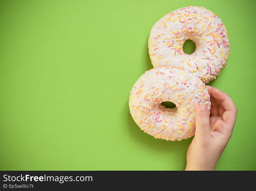 Close up female holds in hand colorful white donut isolated on white background. Proper nutrition or sweets, dessert fast food, dieting morning concept. Copy space for advertisement. Advertising area. Close up female holds in hand colorful white donut isolated on white background. Proper nutrition or sweets, dessert fast food, dieting morning concept. Copy space for advertisement. Advertising area