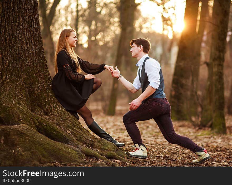 tic date of a loving young couple in classic dress in a fairytale forest park on sunset. tic date of a loving young couple in classic dress in a fairytale forest park on sunset