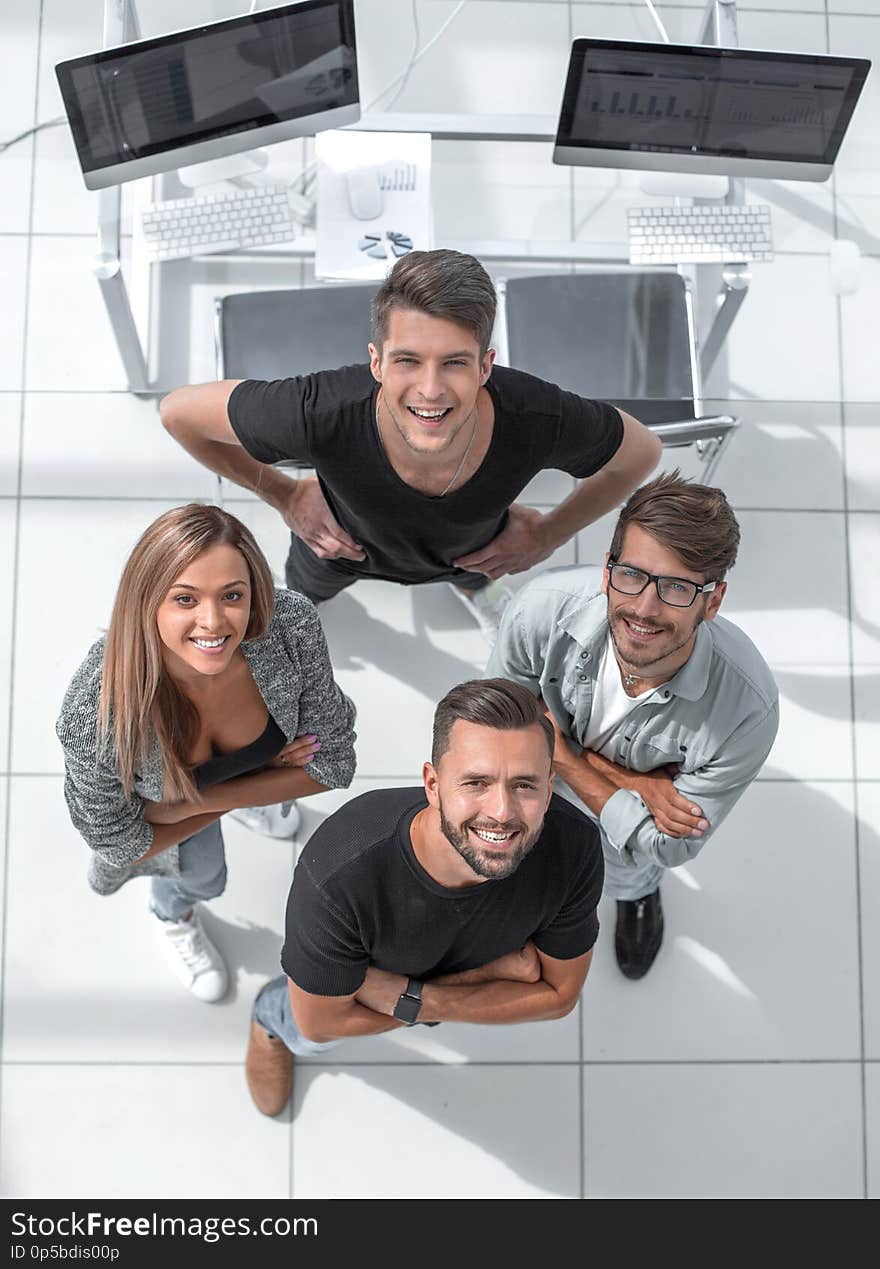 Three young people stand in the office with their arms crossed and look up. One holds his hands on his belt. Three young people stand in the office with their arms crossed and look up. One holds his hands on his belt