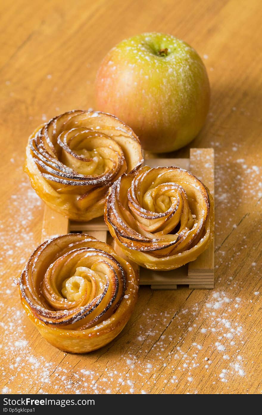 Tasty Apple Rose mini tarts with icing sugar and cinnamon on wooden background. Tasty Apple Rose mini tarts with icing sugar and cinnamon on wooden background