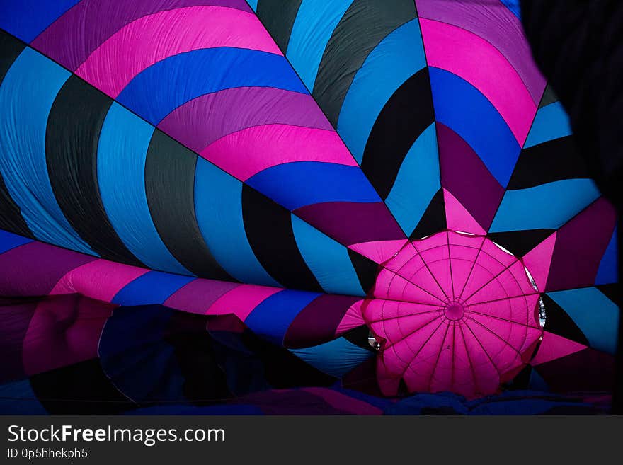 A colorful hot air balloon while on the ground being blown up. A colorful hot air balloon while on the ground being blown up