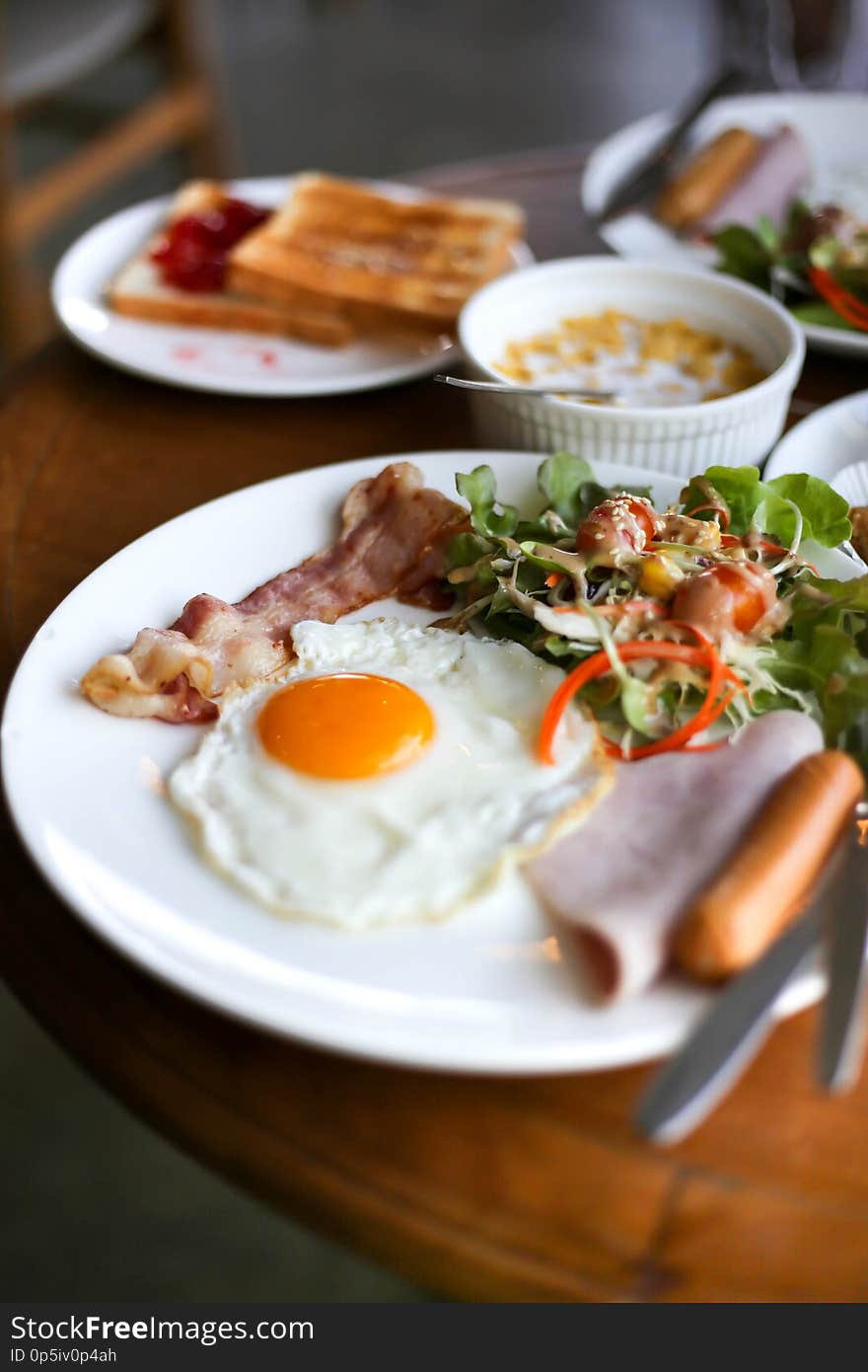 Healthy breakfast spread on a table with coffee, orange juice, fruit, muesli, smoked salmon, egg, croissants, meat and cheese