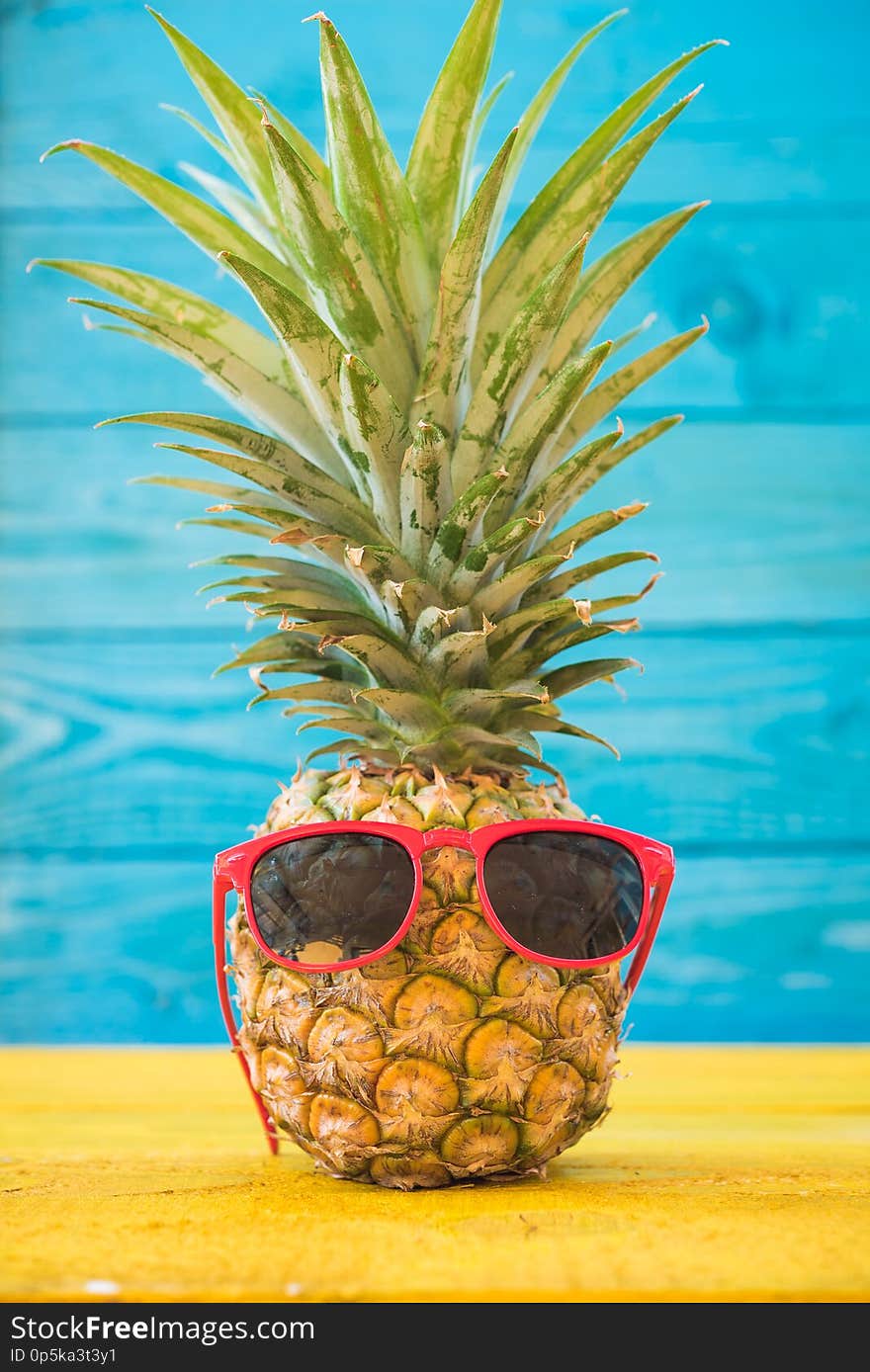 Holiday pineapple have sunglasses on blue wooden background, tropical holiday concept