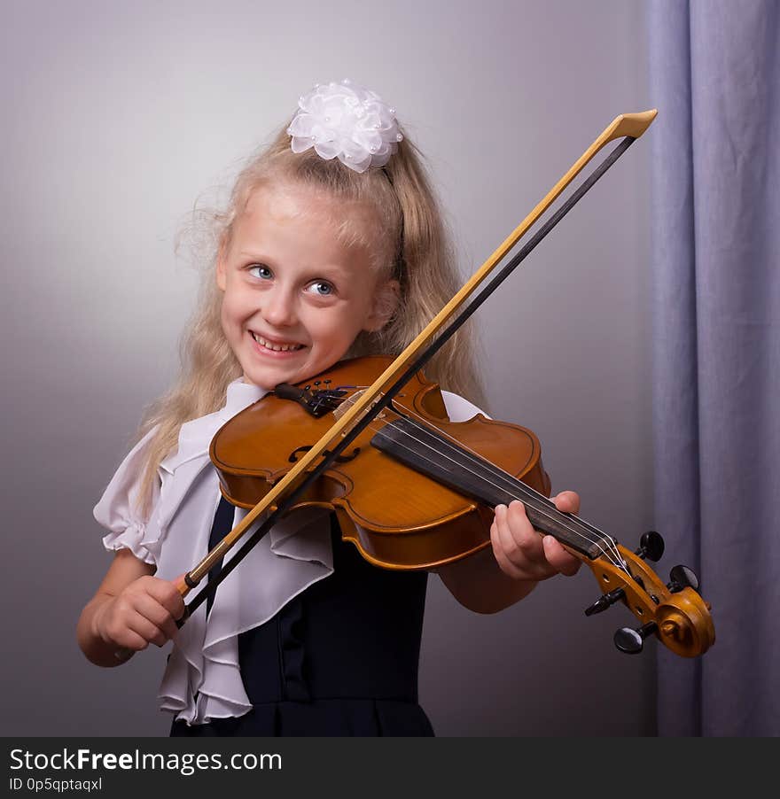 Happy little girl playing violin on gray background