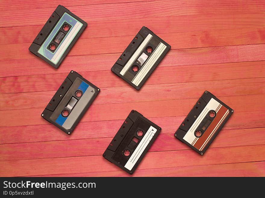 Audio cassettes tape group lay on pink wooden plank composition. Audio cassettes tape group lay on pink wooden plank composition