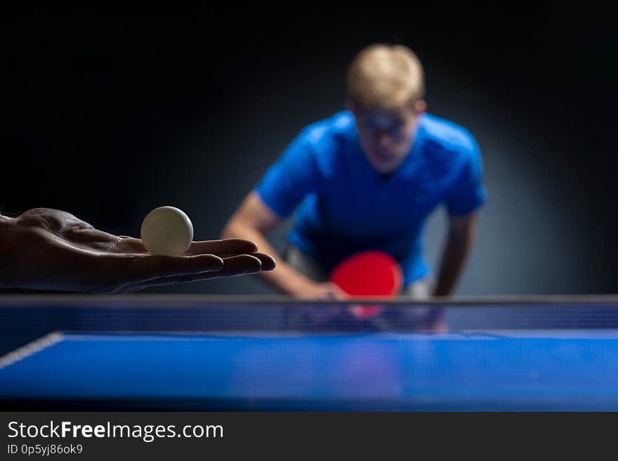 Portrait of young man playing tennis on black background