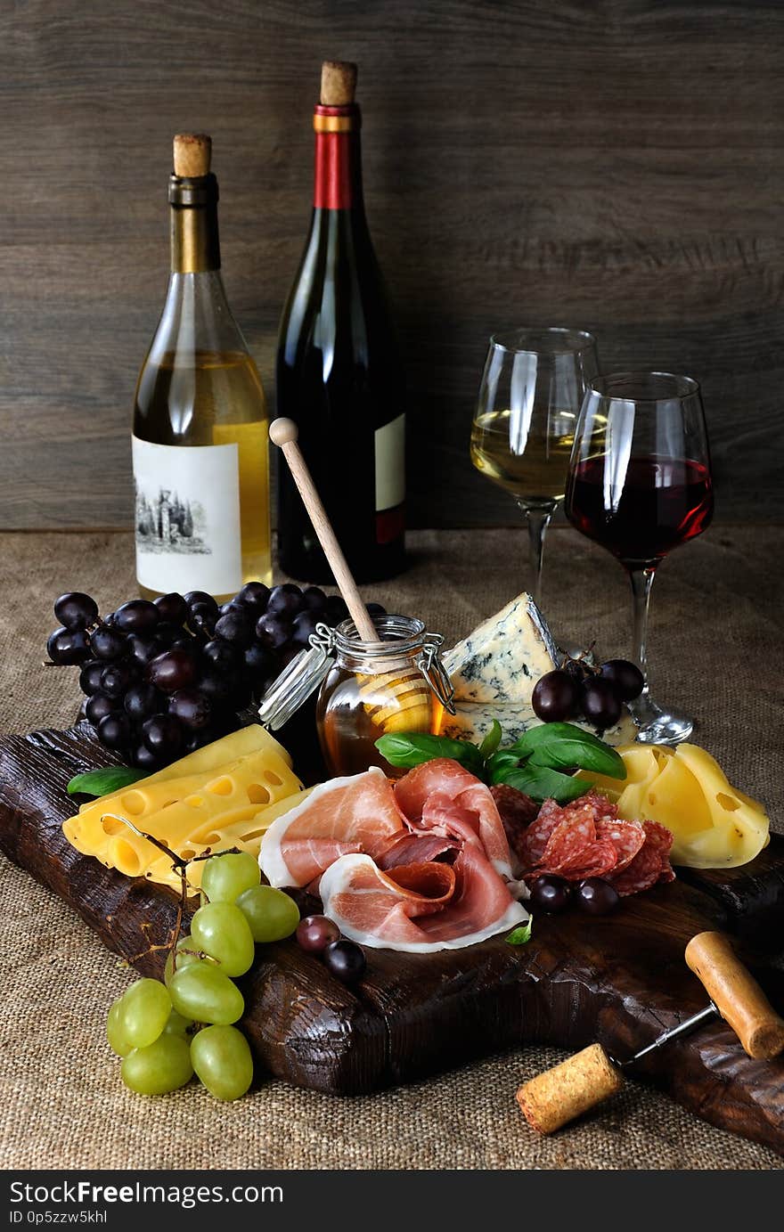 Antipasto catering platter with jerky bacon, prosciutto, salami, cheese and grapes on a wooden background. Antipasto catering platter with jerky bacon, prosciutto, salami, cheese and grapes on a wooden background