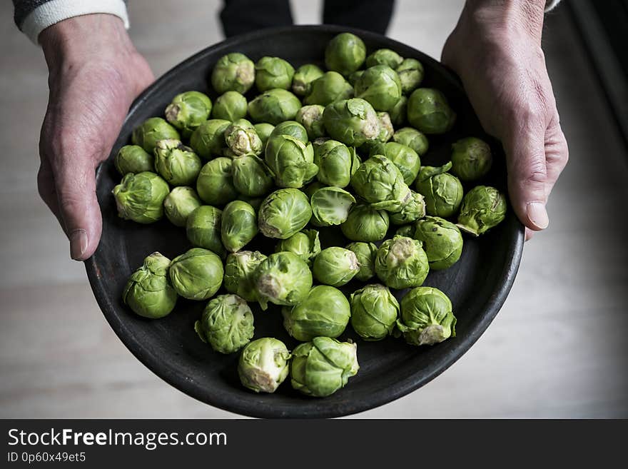 Man shows Brussels sprouts on black plate