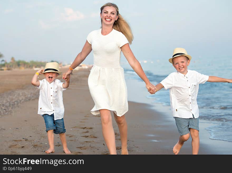 Family walking on the evening beach during sunset.Mother and two sons.