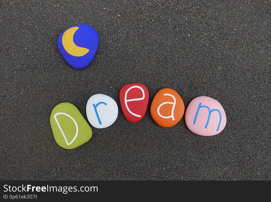 Dream text with multi colored sea stones over black volcanic sand