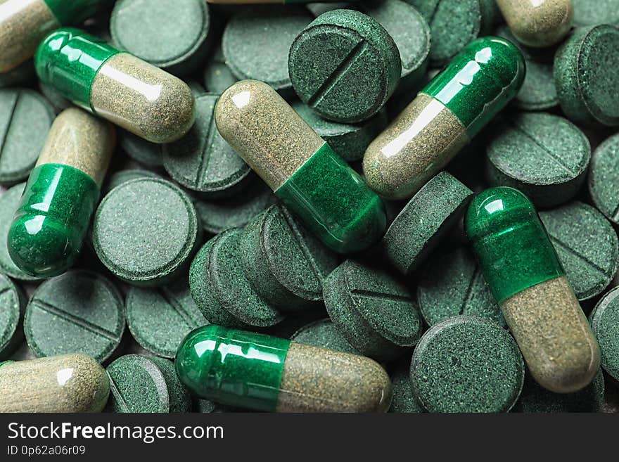 Green spirulina pills and capsules as background