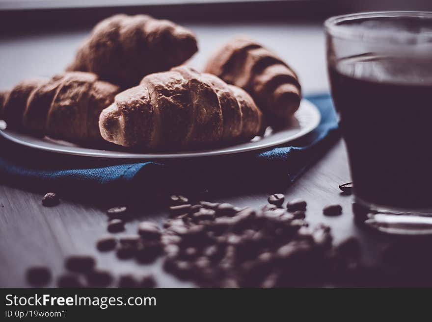 The concept of breakfast. Dessert and coffee beans. Mate moody color. Macro shot of fresh croissants and coffee on a black background.