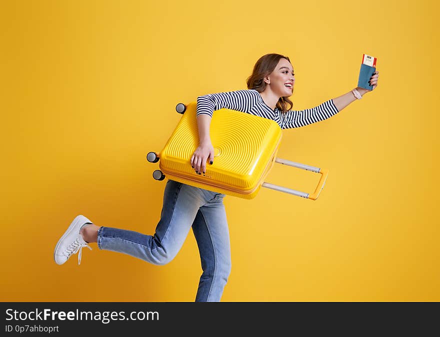 Go on an adventure! Happy woman going traveling. Young person with suitcase on color yellow background