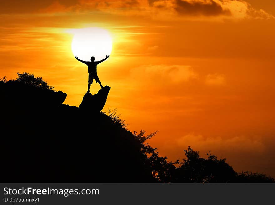 Man standing on the top of the mountain looking at red sky sunset background