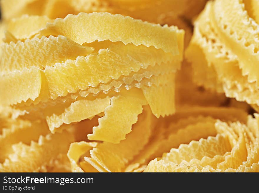 Beautiful nest of  fettuccine pasta  close up , thin ribbons of pasta with geometrical edges and rough surface. Beautiful nest of  fettuccine pasta  close up , thin ribbons of pasta with geometrical edges and rough surface