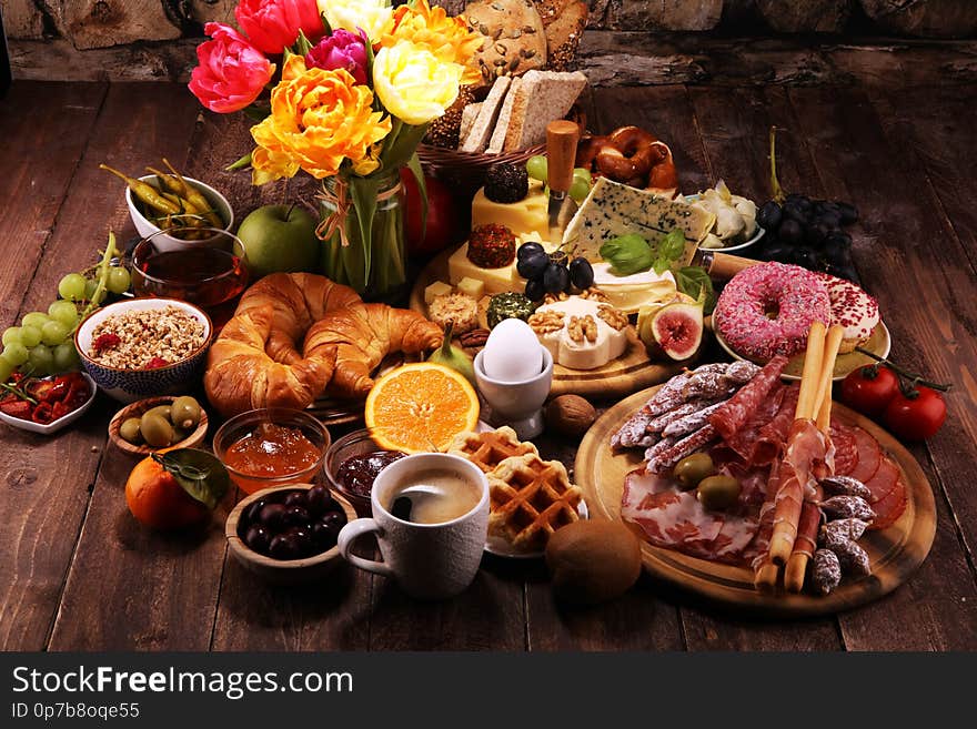 Breakfast on table with bread buns, croissants, coffe and eggs