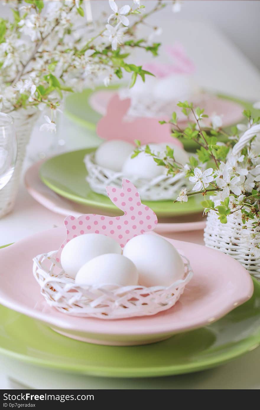 Happy easter. Decor and table setting of the Easter table is a vase with pink tulips and dishes of pink and green color. Selective focus