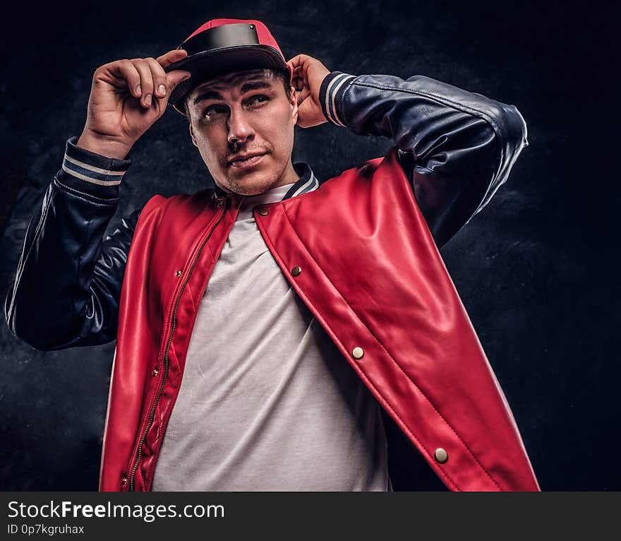 Close-up portrait of a handsome man dressed in a hip-hop style. Studio photo against a dark wall