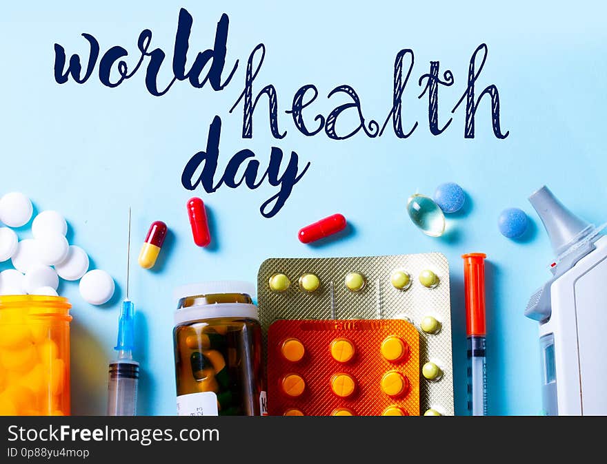 Healthcare concept - pills and medical instruments top view close up border on blue with world health day words. Healthcare concept - pills and medical instruments top view close up border on blue with world health day words