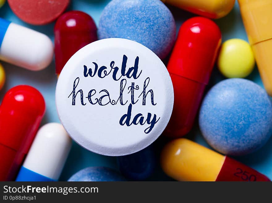 Pile of colorful medical pills close up with world health day words. Pile of colorful medical pills close up with world health day words