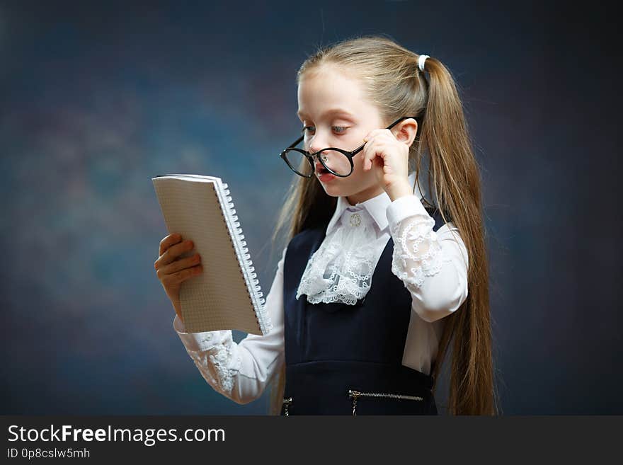 Schoolgirl Wear Glasses Uniform Look at Notebook. Camera Shot on Dark Background. Pensive Little Child with Writing Pad. Clever Elementary School Scholar Study, get Knowledge, do Homework