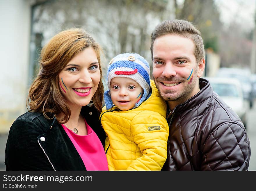 Family portrait, parents with one child sitting together, smiling. They have the Romanian on their faces. Family portrait, parents with one child sitting together, smiling. They have the Romanian on their faces.