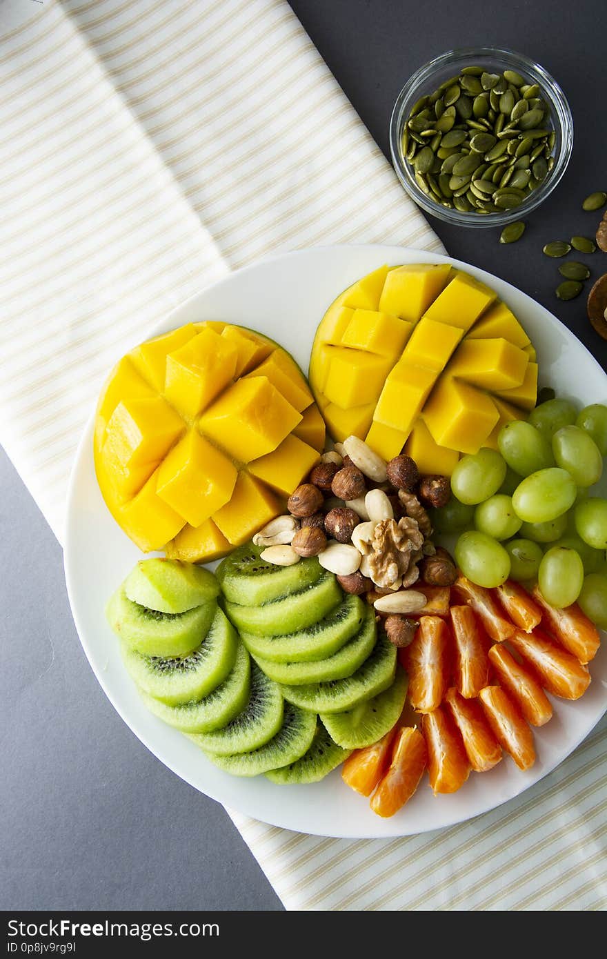 Delicious fruits platte isolated. Mango, kiwi, citrus, nuts, grapes. Mix of various exotic fruits. Healthy fruit salad, healthy