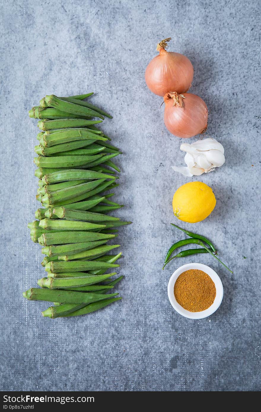 Fresh okra, fresh lady fingers, fresh bhindi. Ingredients for an Indian okra recipe. Onions, masala, lemon, green chillies, garlic and okra. Healthy vegan meal. Fresh okra, fresh lady fingers, fresh bhindi. Ingredients for an Indian okra recipe. Onions, masala, lemon, green chillies, garlic and okra. Healthy vegan meal.