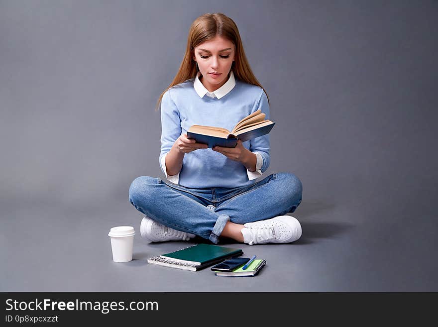 Student reading book sitting on the floor. Student concept. Studio