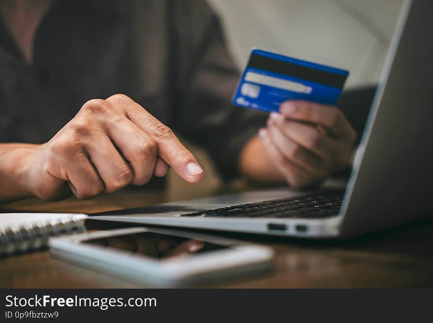 Businessman holding credit card and typing on laptop for online shopping and payment makes a purchase on the Internet, Online