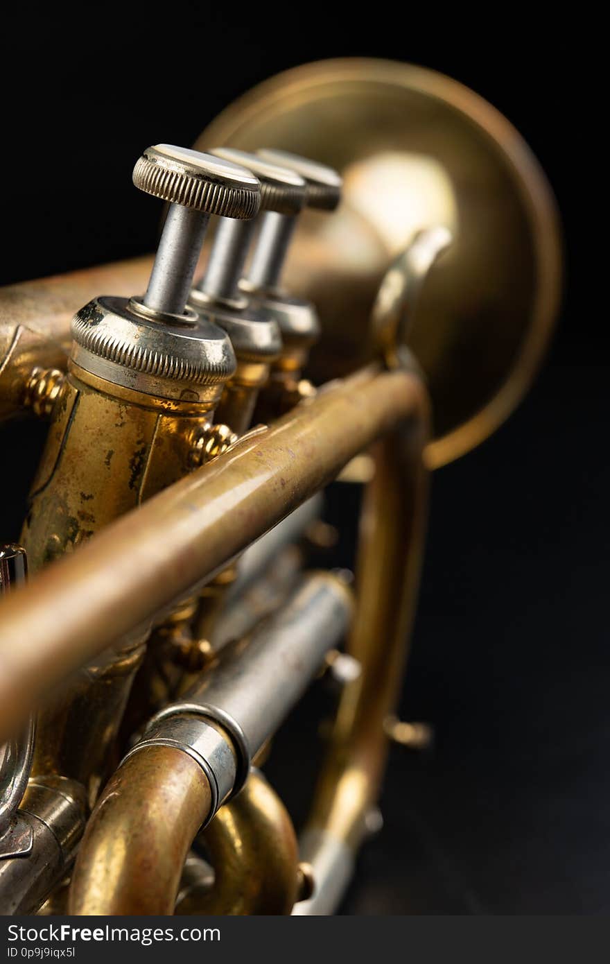 Old coated patina trumpet on a dark table. An inedible musical instrument. Dark background.q