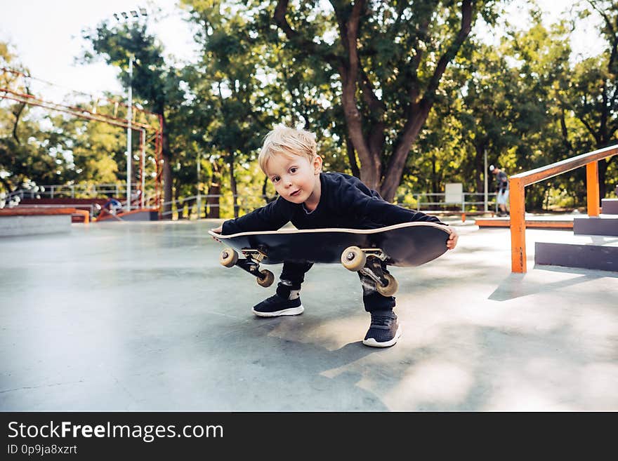 Little boy trying to pick up a skateboard