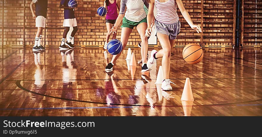 High school kids practicing football using cones for dribbling drill in the court