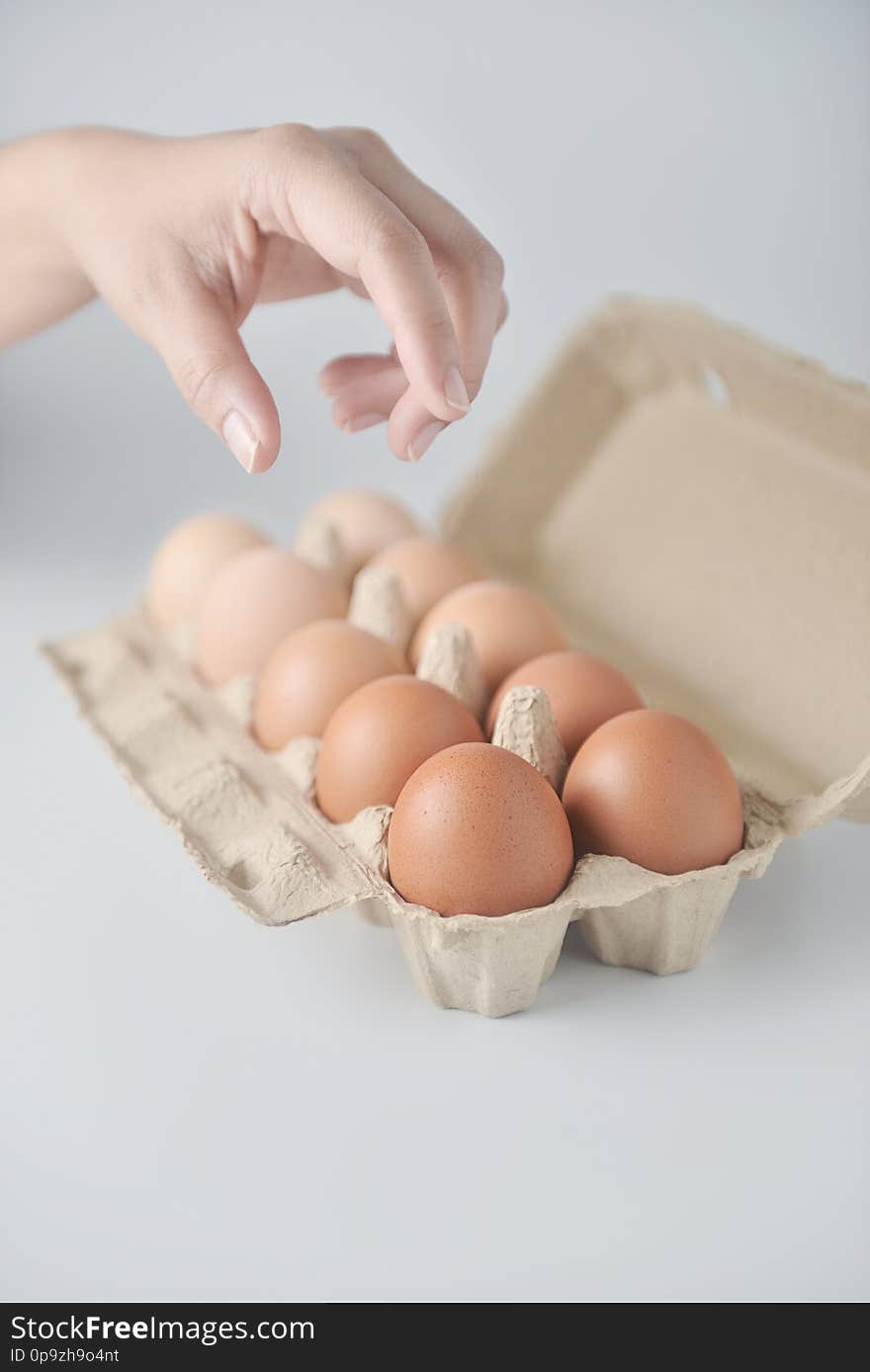 Hand are picking chicken eggs are arranged in a gradient color tone in eco carton on white background.perspective view. Hand are picking chicken eggs are arranged in a gradient color tone in eco carton on white background.perspective view