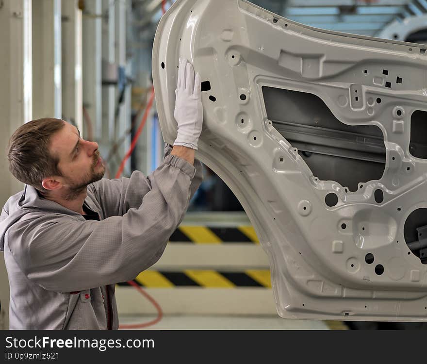 An employee of the car body painting shop checks the quality