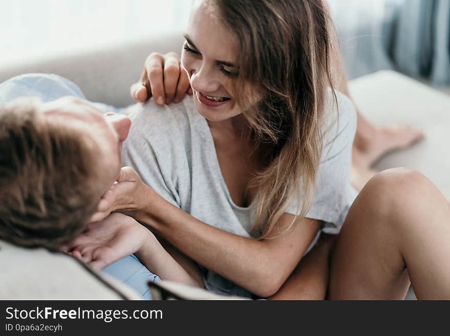 Beautiful young couple embracing while sitting face to face on a couch at home