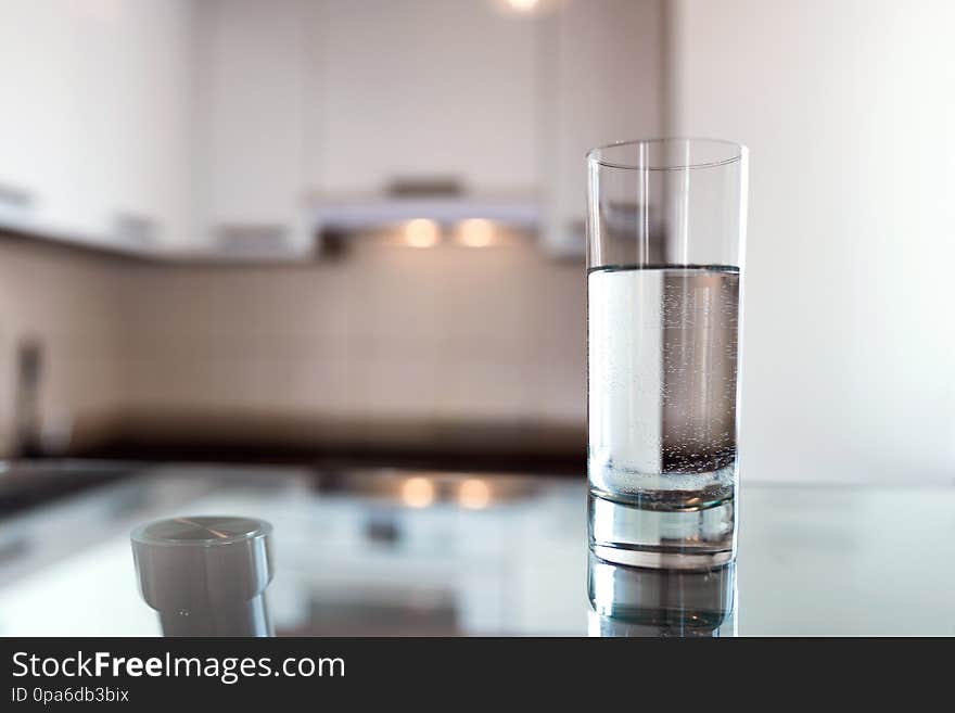 A glass of fresh water on the background of a modern kitchen. With copy space for your design.