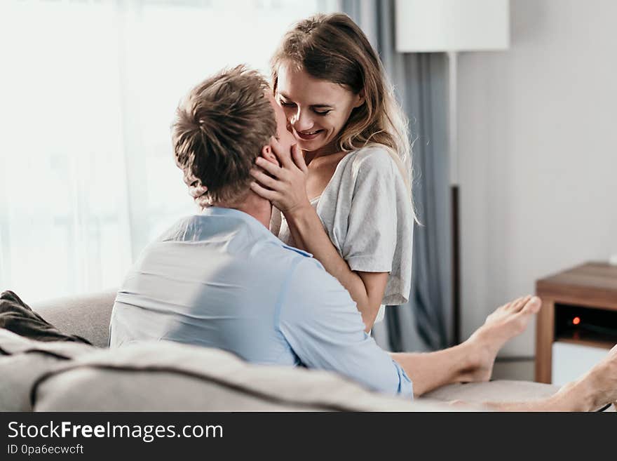 Beautiful young couple bonding and smiling while lying on the couch