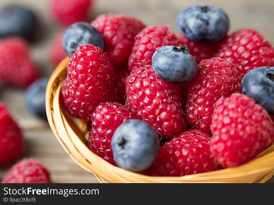 Raspberries and blueberries in a basket on a wooden table
shallow DOF